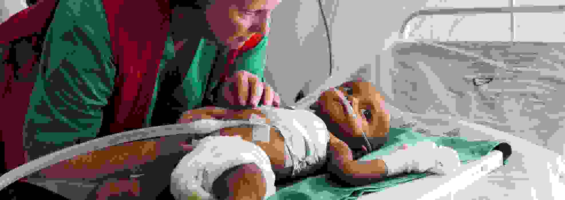 En av Röda Korsets biståndsarbetare tar hand om ett spädbarn på ett fältsjukhus.