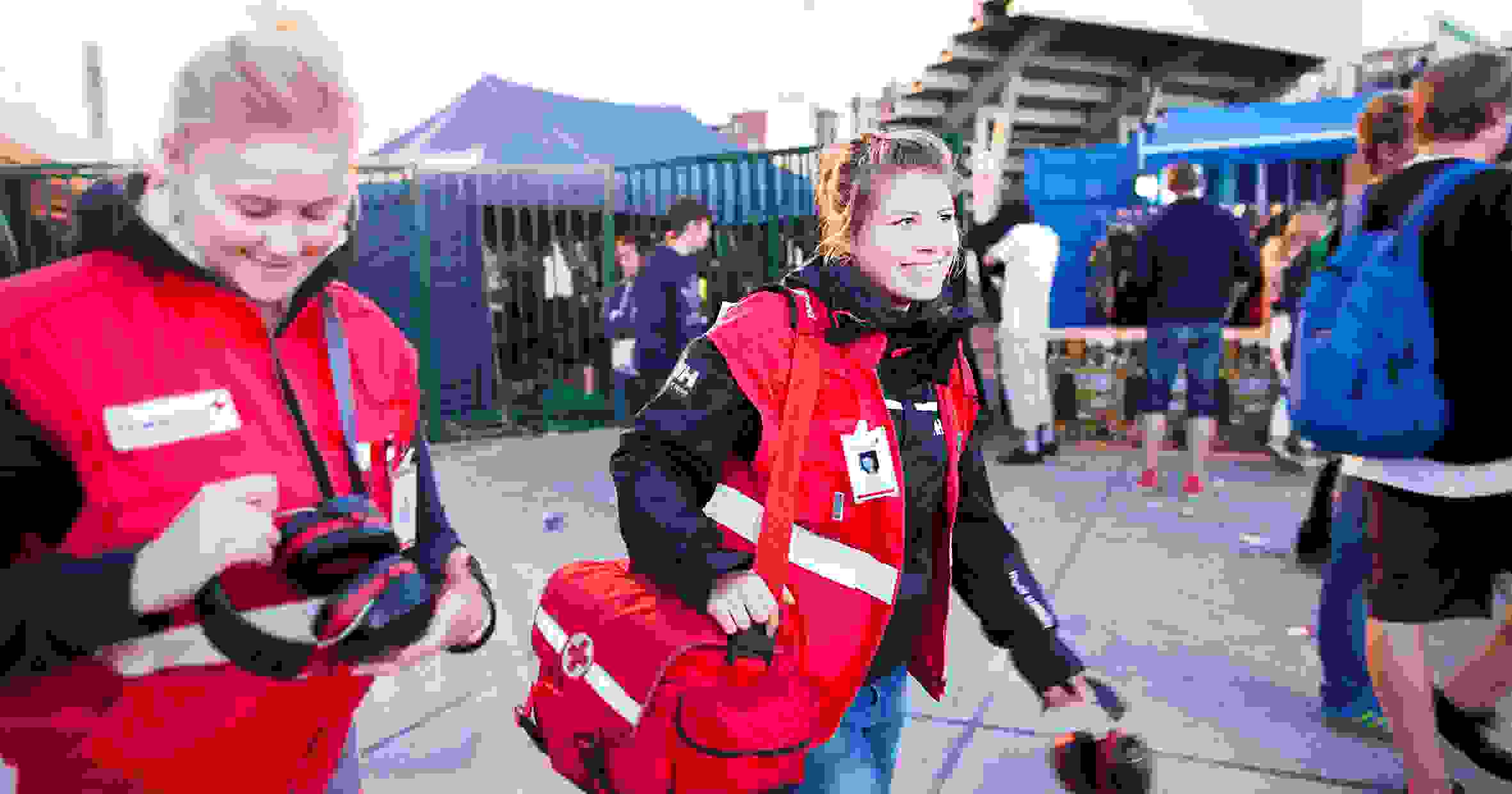 Leende frivilliga första hjälpen-jourhavande från Röda Korset går runt på ett festivalområde.