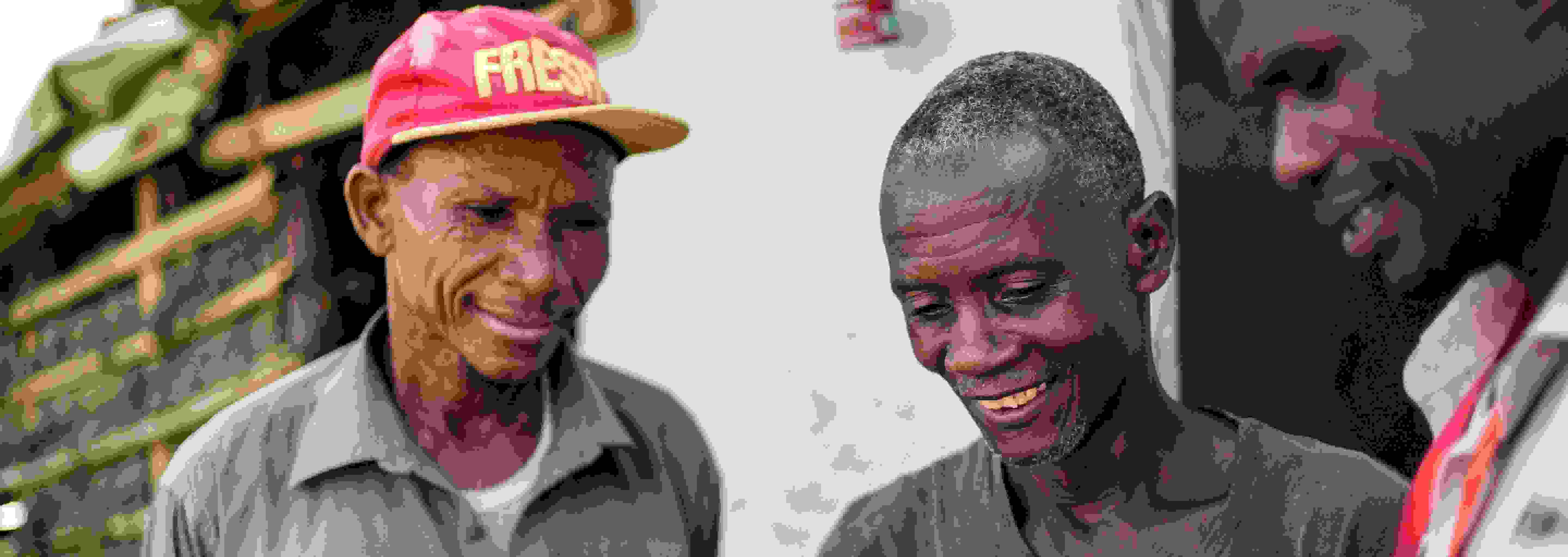 Kolme hymyilevää afrikkalaismiestä tutkii dokumenttia, jossa on tietoa kadonneesta omaisesta.