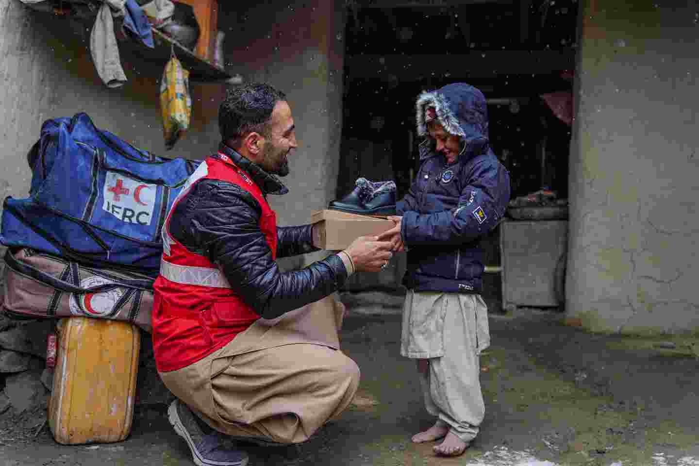En anställd på Röda Korset ger ett hjälppaket till ett barn.