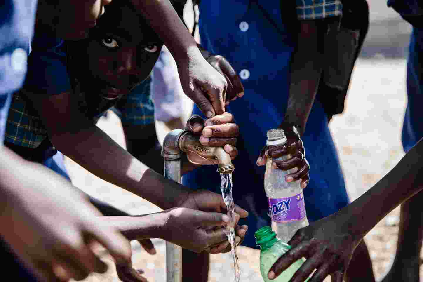 Barn som fyller vattenflaskor.