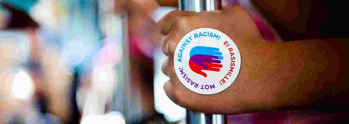 Kampanjlogon Mot rasism på en hand som håller i en stång på en spårvagn.