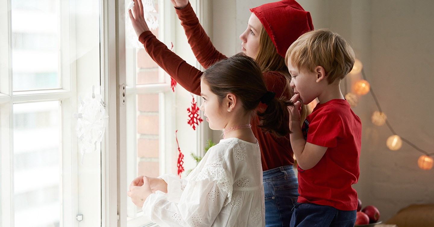 Tre barn tittar ut genom fönstret.