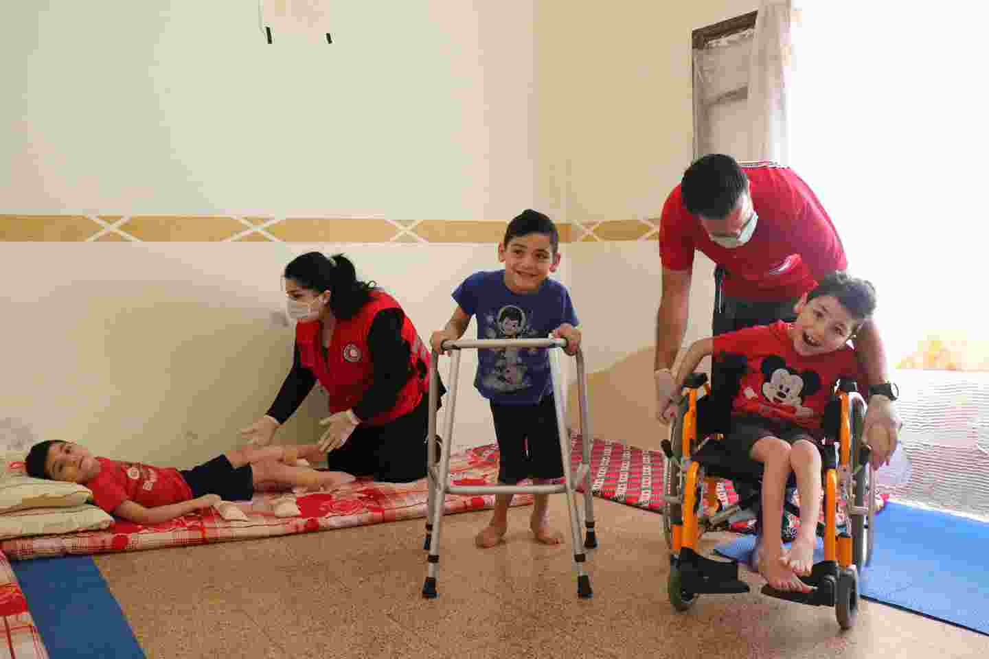 Tre leende syrier får hjälp av två arbetare från Röda halvmånen.