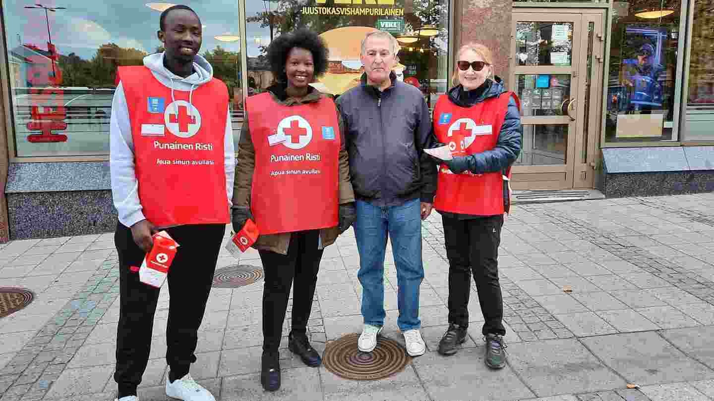 Fyra leende personer står framför ett köpcentrum. Två av dem håller Hungerdagens insamlingsbössa i sin hand, tre har Röda Korsets insamlingsväst.