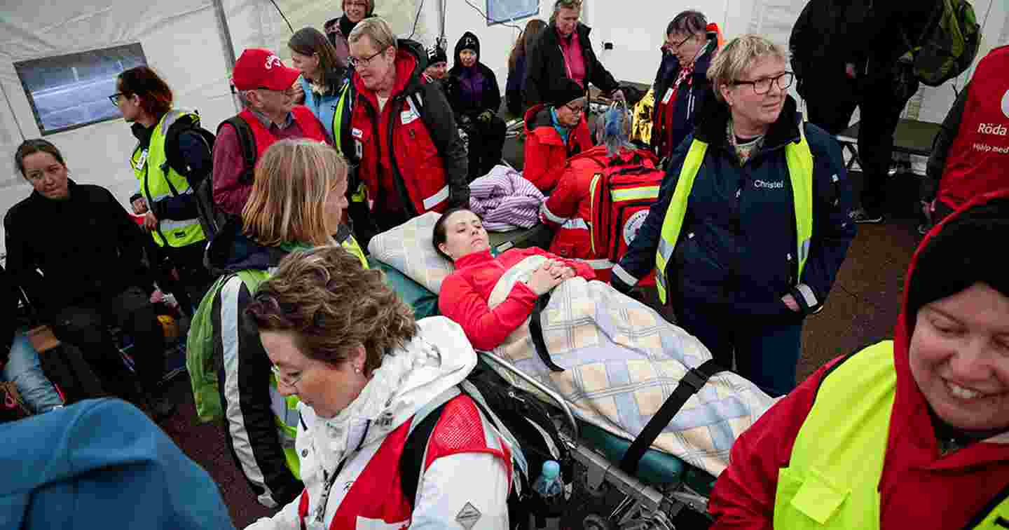 Personer i Röda Korsets kläder i Västra Hamnen. I mitten ligger en människa på en bår.