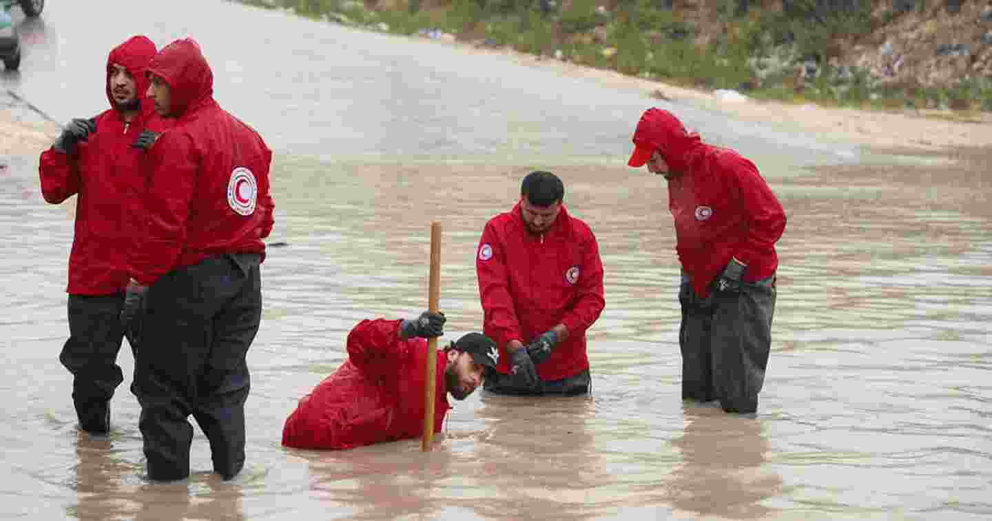 Personer i Röda Halvmånens västar står i översvämningsvattnet.