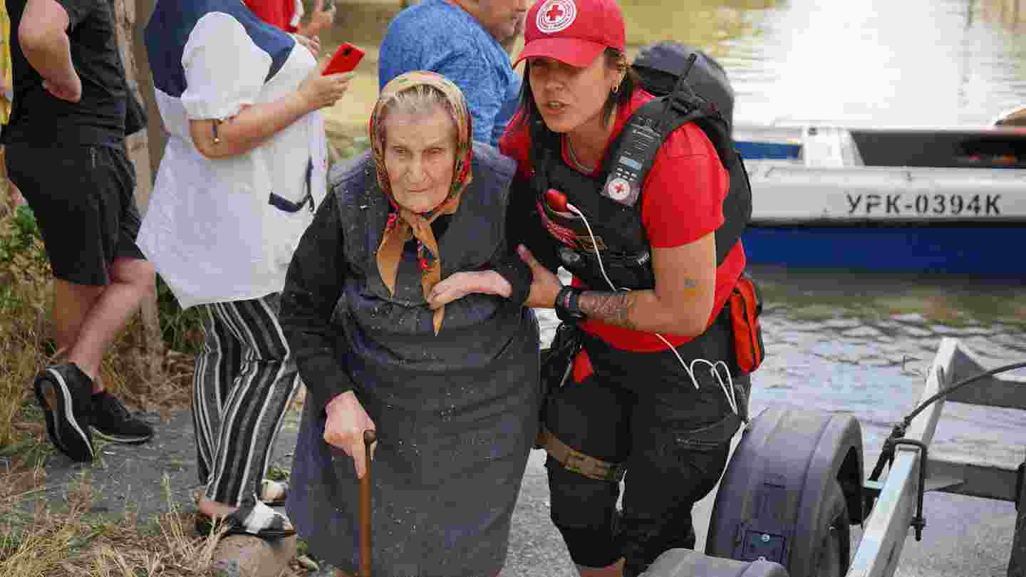 En frivillig på ukrainska Röda Korset hjälper en äldre person att gå.