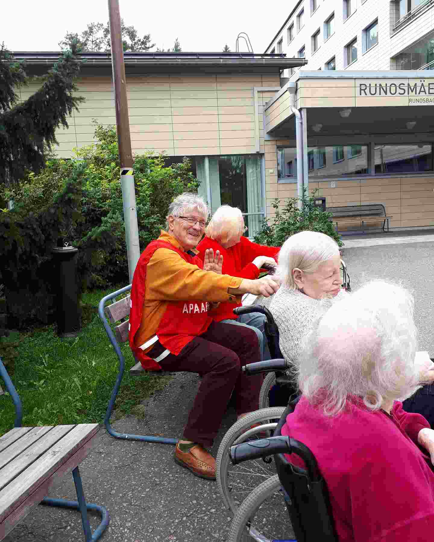 En leende frivillig från Röda Korset är ute med äldre boende från ett servicehus.