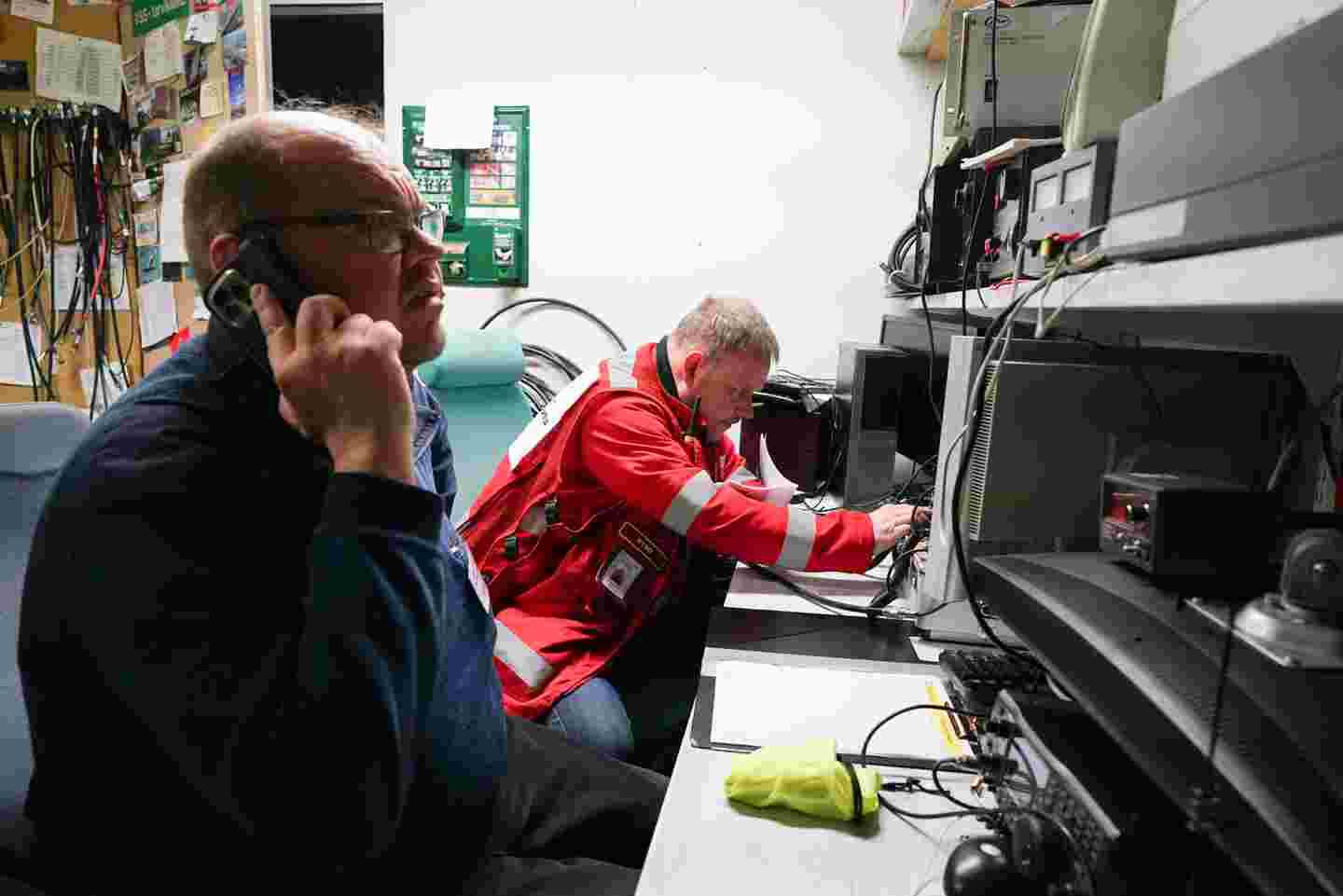 Frivilliga från Röda Korset och Frivilliga räddningstjänsten i ett tekniskt rum bland apparater. En av de frivilliga talar i telefonen.
