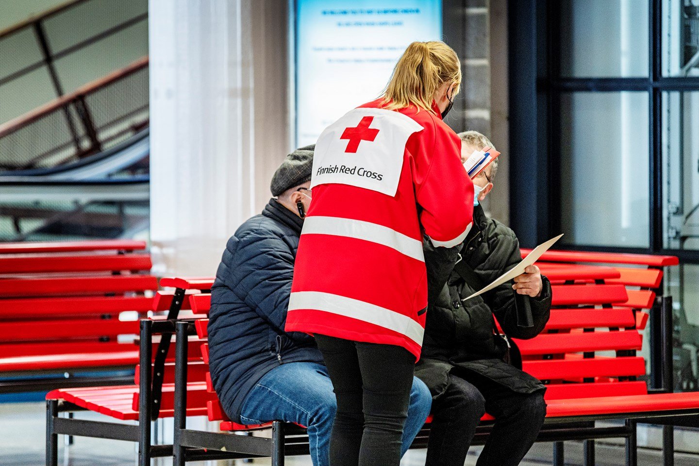 En frivillig i Röda Korsets kläder pratar med flyktingar i hamnen.