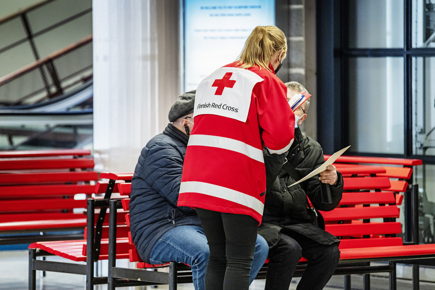 En frivillig i Röda Korsets kläder pratar med flyktingar i hamnen.