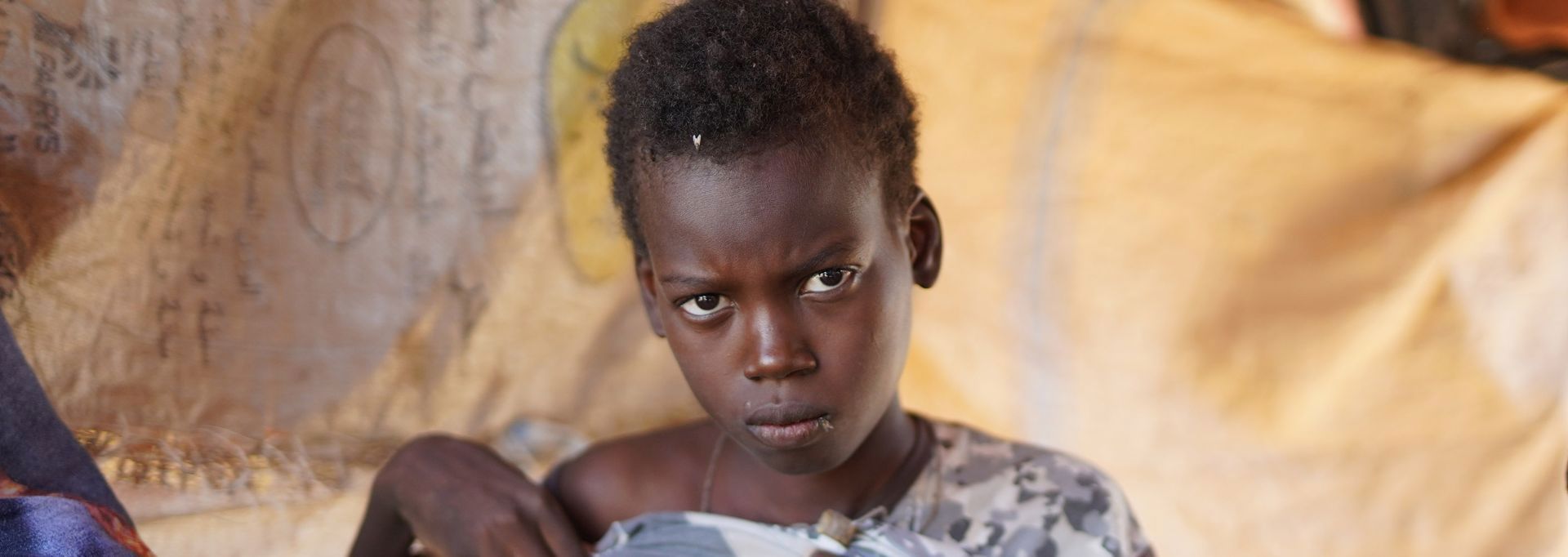 Två av Röda Korsets frivilliga i röda insamlingsvästar håller i insamlingsbössor. Bredvid dem finns en ungefär två meter hög insamlingsbössa.