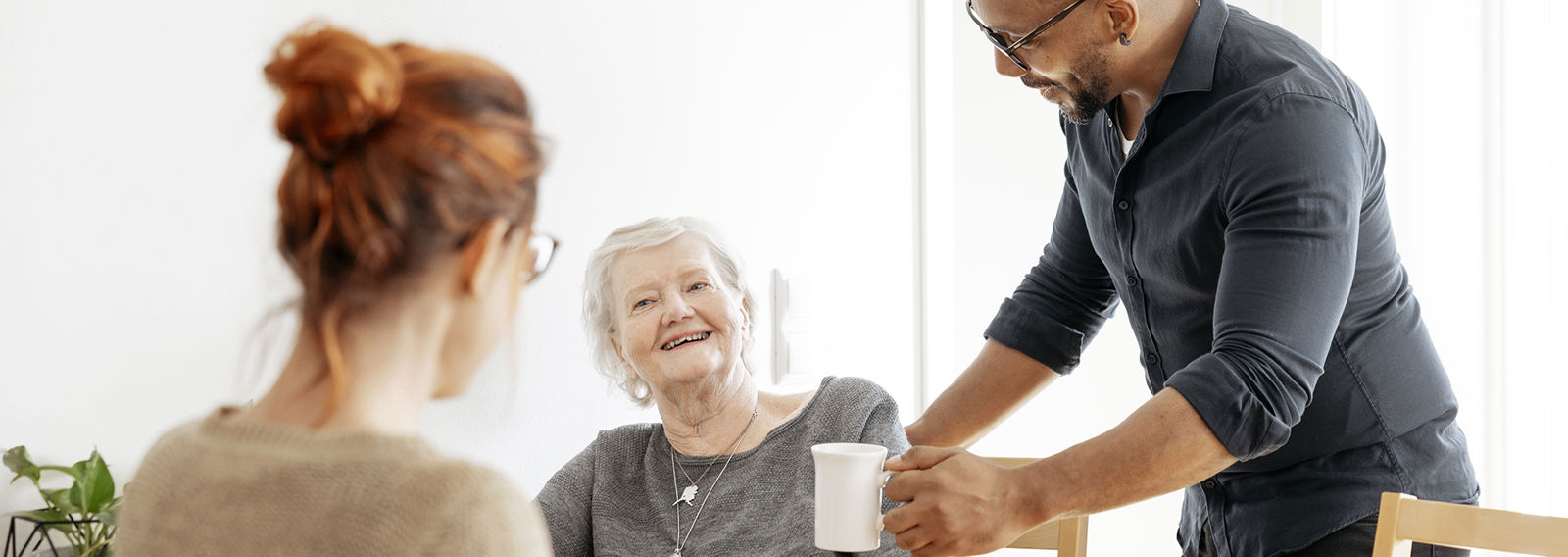 Två kvinnor står bredvid varandra i ett vintrigt landskap. Den yngre kvinnan i Röda Korsets väst för frivilliga tittar vänligt på den äldre.