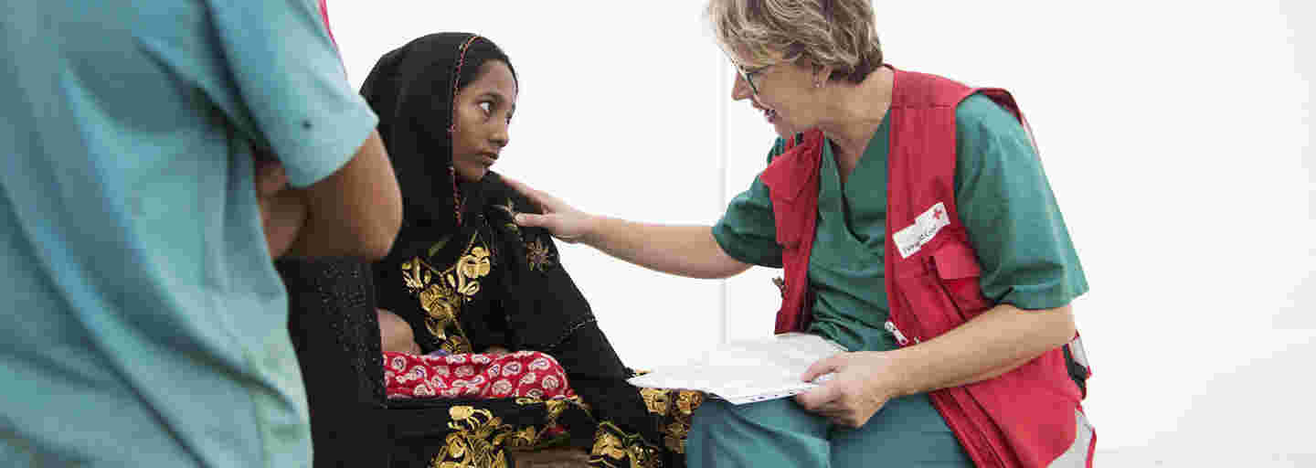 En ung bangladeshisk kvinna pratar med en Röda Korsets biståndsarbetare på ett fältsjukhus.