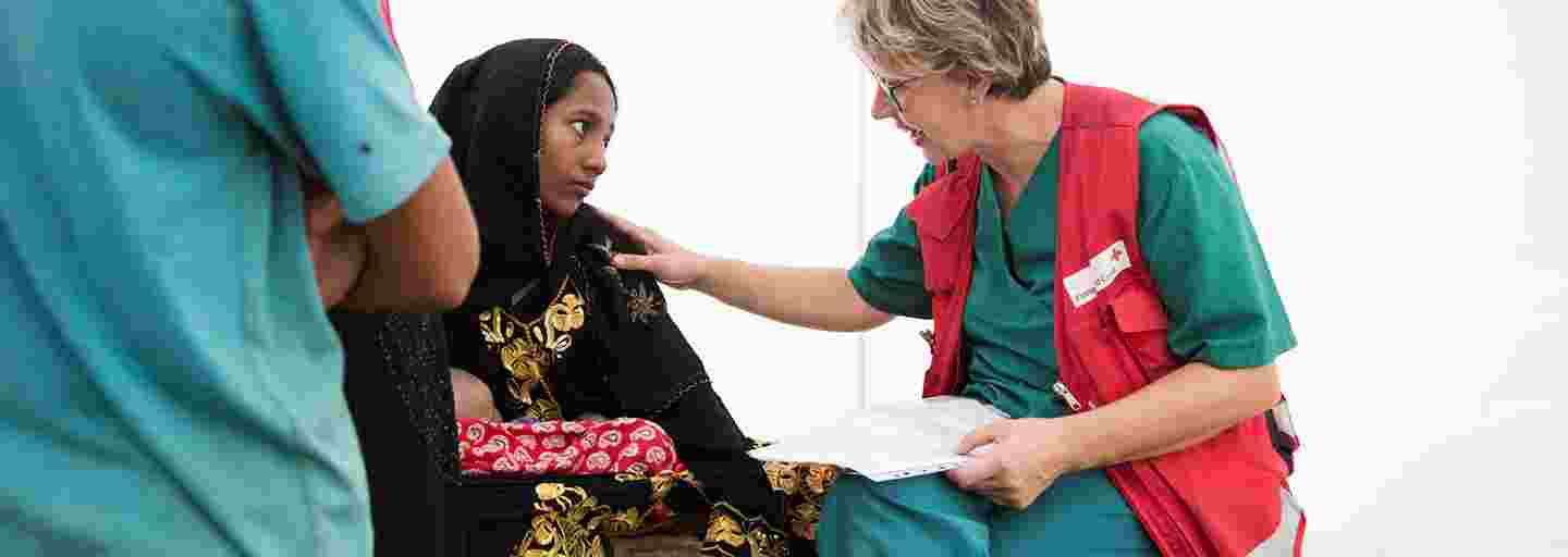En ung bangladeshisk kvinna pratar med en Röda Korsets biståndsarbetare på ett fältsjukhus.