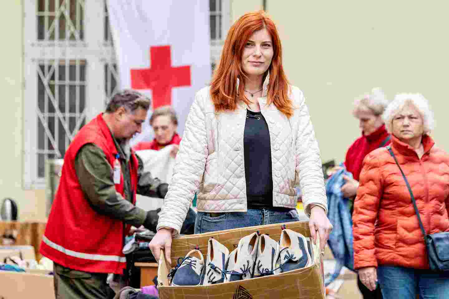 En kvinna med en skokartong i handen, i bakgrunden andra människor.