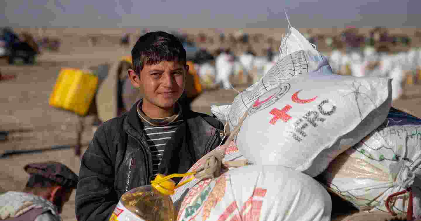 En afghansk ungdom hämtar Röda Korsets biståndsmaterial.