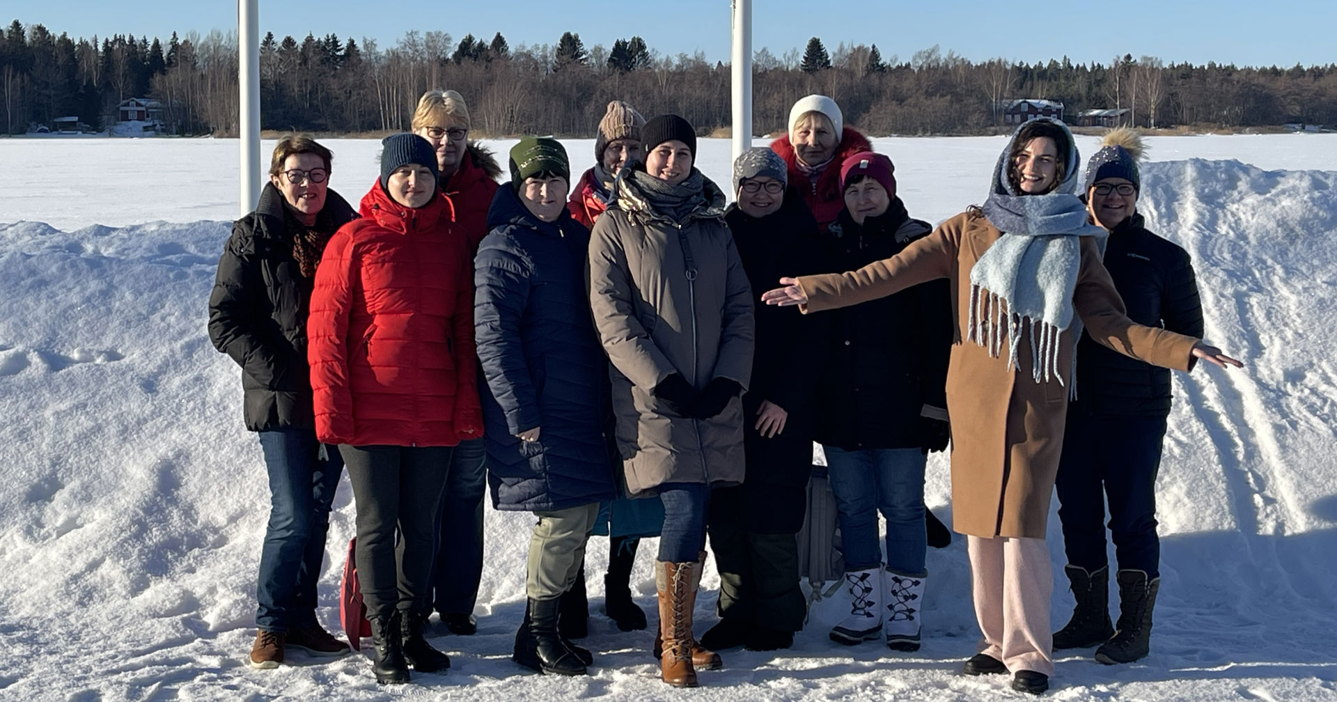En frivillig inom Röda Korset och deltagarna i Röda Korsets kurs på ukrainska ler tillsammans i ett vinterlandskap.